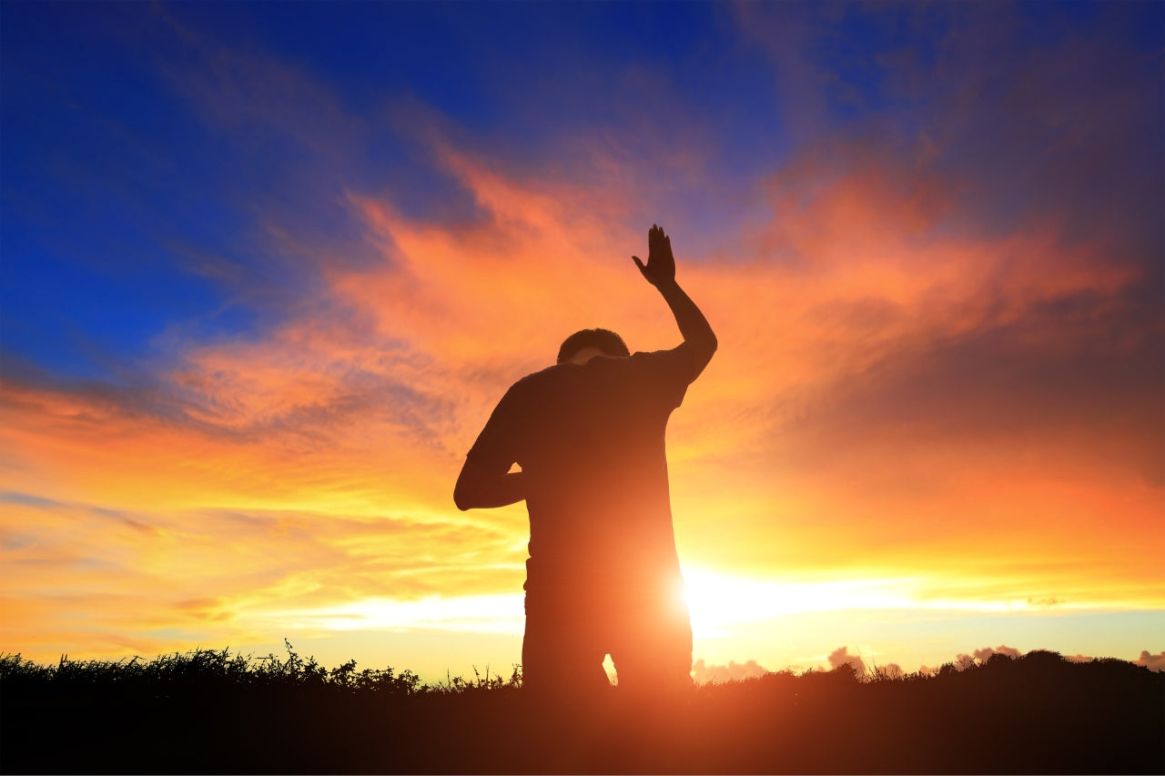 man worshipping at sunrise